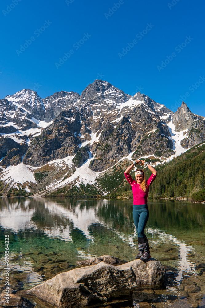 a woman stands and shows a heart by a beautiful lake in the mountains. Famous mountains lake Morskie oko or sea eye lake In High Tatras. Five lakes valley