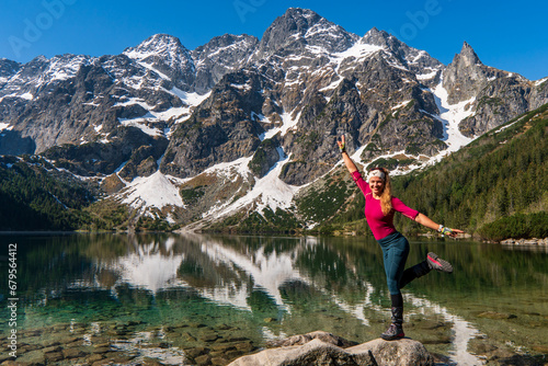 Young girl enjoying beauty of nature looking at mountain lake in famous mountains lake Morskie oko or sea eye lake In High Tatras. Five lakes valley. Adventure travel in Slovekia, Europe.