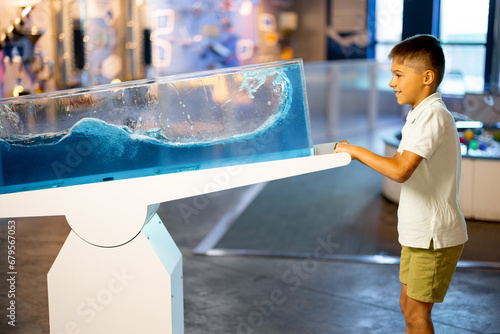 Little boy learns physics interactively on a model that shows physical phenomena while visiting a science museum. Concept of children's entertainment and learning