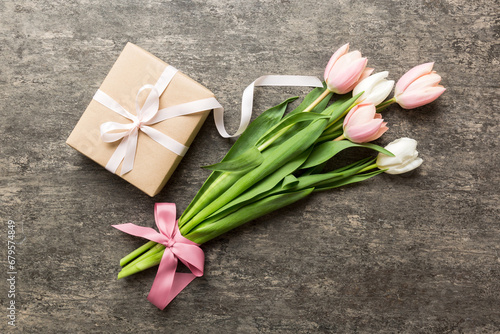 Pink tulips flowers and gift or present box on colored table background. Mothers Day  Birthday  Womens Day  celebration concept. Space for text top view