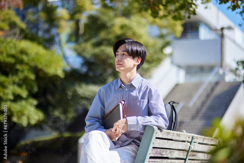 Fototapeta premium 大学キャンパスのベンチに座る日本人大学生の男性