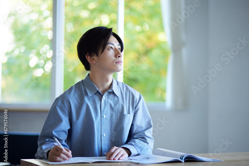 家のリビングで勉強をする日本人大学生の男性 photo