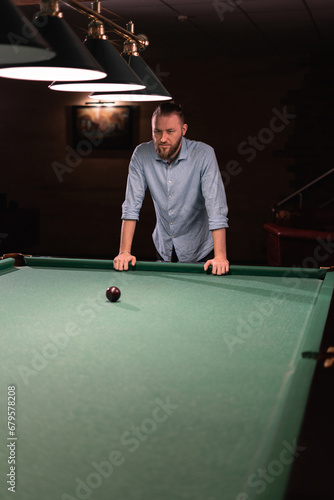 Successful man standing at the billiard table in a nightclub about to start playing billiards