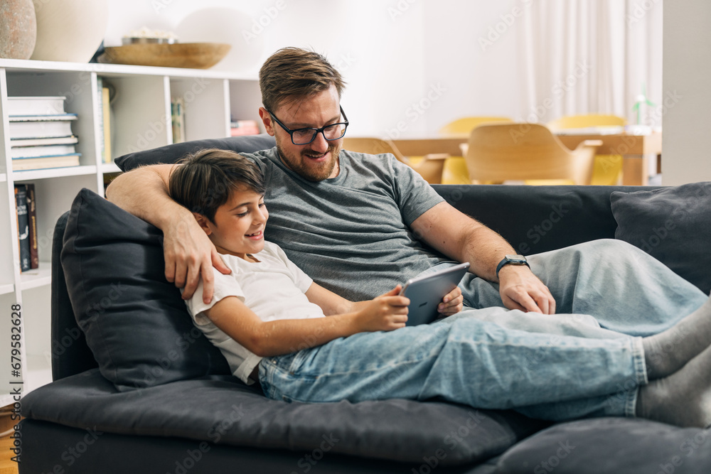 Father and son watching motion picture together using tablet.