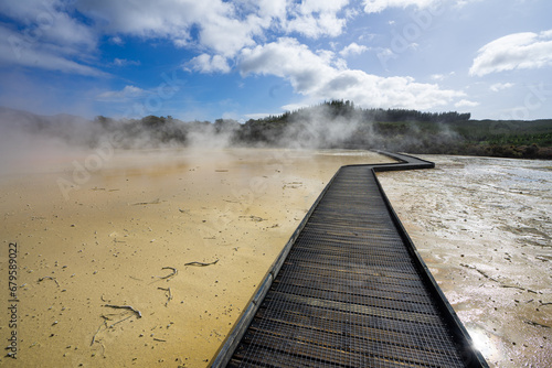 Wooden path leading through the travertine with steam rising in the air at Wai o Tapu.