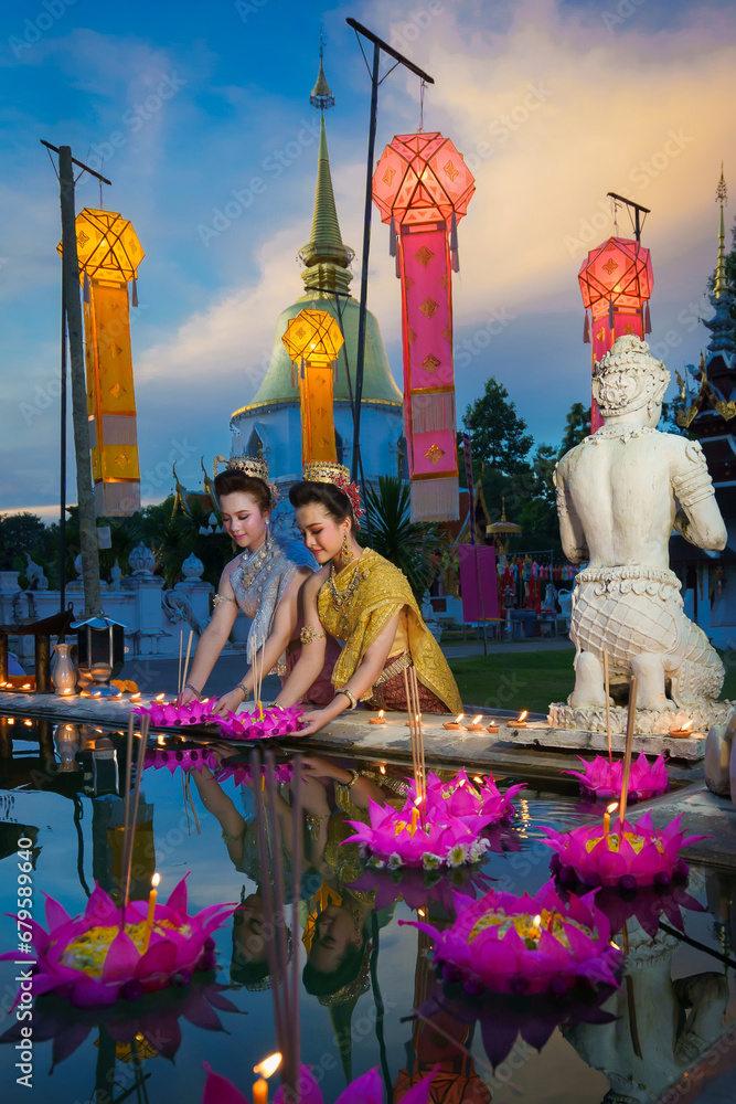 Fototapeta premium Pretty Asian Thai women holding a Krathong floating on water, Asian women in traditional Thai dress bring Krathong to float on Loy Krathong Festival Day, Popular traditions culture of Thailand.