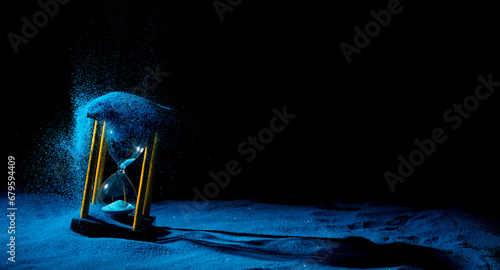 Hourglass is sand of time age, Life pour blue sand into hourglass to add more limited time. Deadline extended time management hope concept hour glass. Black background shadow life clock passing by