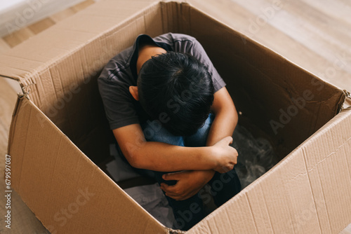 Little boy sitting alone hugging knee in the box. Mental health concept.  photo