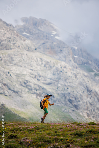 boy with a backpack on a hike against the backdrop of the mountains. child traveler with backpack, hiking, travel, mountains in the background, kids summer vacation. © zhukovvvlad