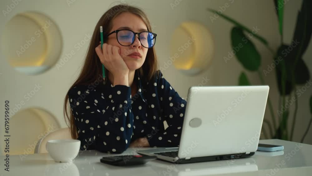 A sad woman works in an office, a business woman is bored looking at a laptop screen A sad woman works in an office, a business woman is bored looking at a laptop screen