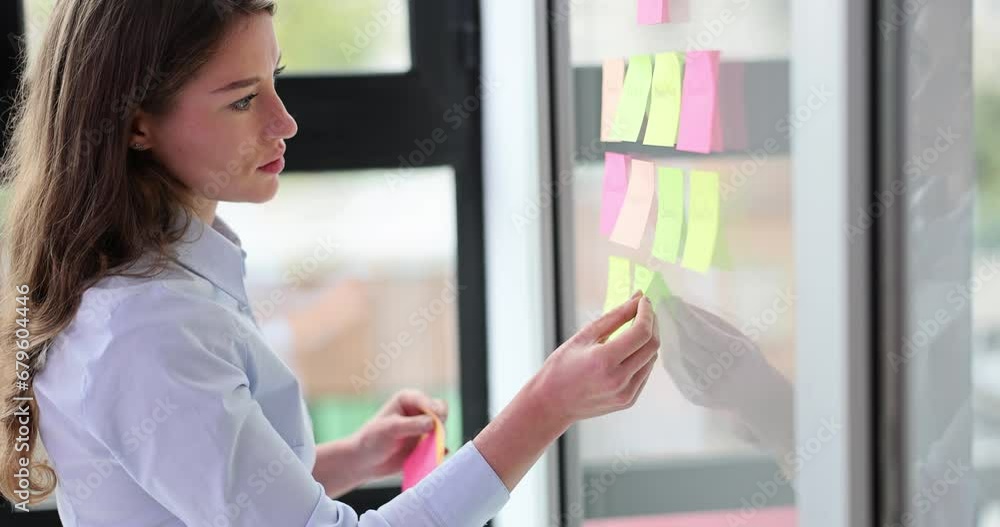 Businesswoman gluing colored stickers with ideas on glass Businesswoman gluing colored stickers with ideas on glass
