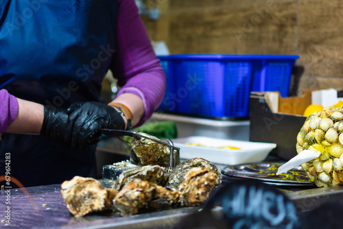 An expert hand deftly handles a tool to open an oyster in a traditional market