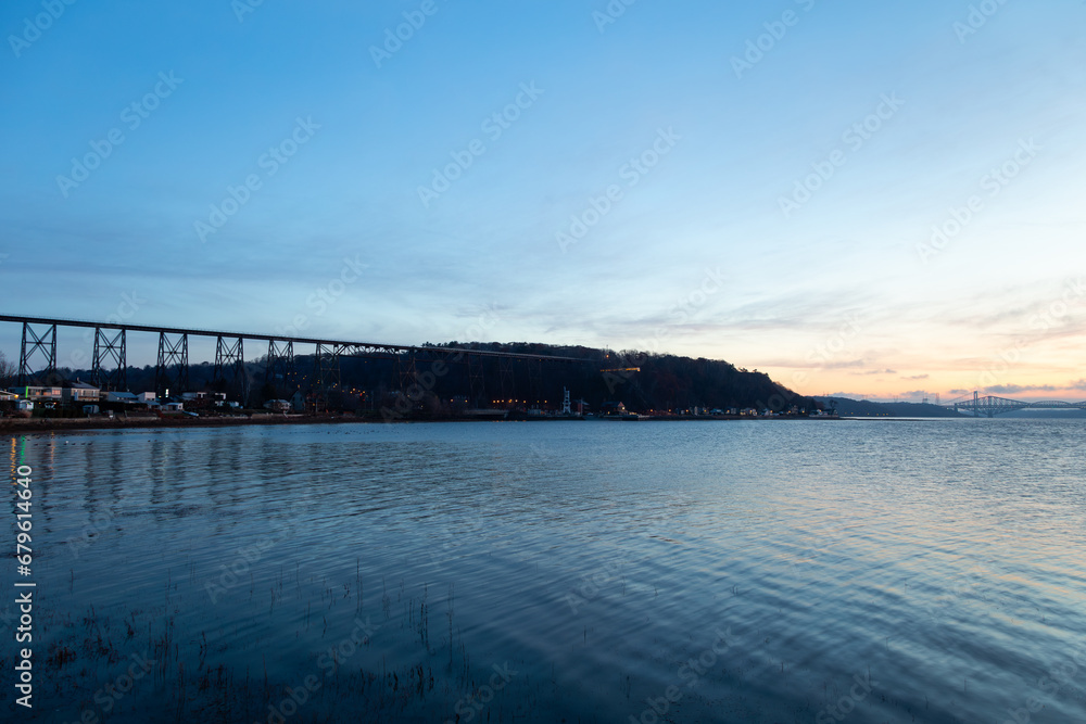 View of the 1908 railway trestle bridge and its reflection in the St. Lawrence River seen during a blue hour late fall sunrise, Quebec City, Quebec, Canada