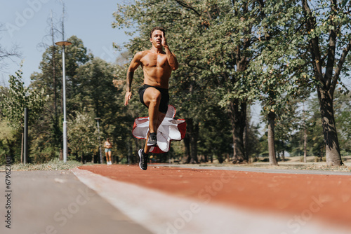Fit, Caucasian male athlete running with parachute on a race track in the park on a beautiful sunny, summer day.