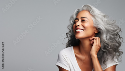 Portrait of an elegant mature woman with smooth healthy skin, long gray hair, and a joyful smile. Cosmetics and beauty advertising.