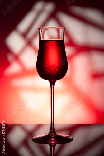 Glass of wine on a red background..Glass of wine with drink on a red abstract background.