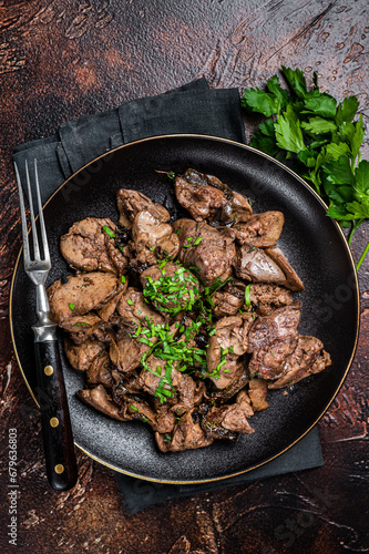 Fried chicken liver with onions and parsley in a plate. Dark background. Top view