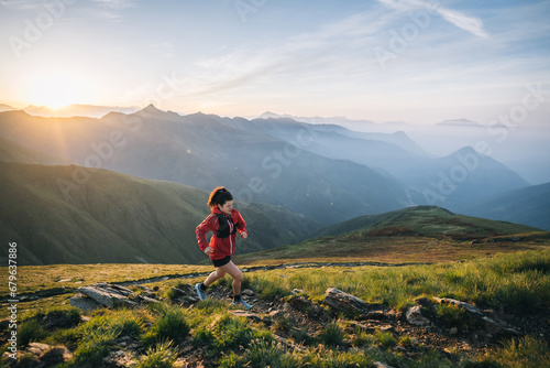 Female trail runner ascending alpine trail in the mountains at sunrise © SwissOutdoor