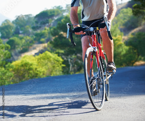 Cycling, fitness and legs of man on a bicycle in road for training, wellness or sport outdoor. Health, exercise or male athlete on a bike in a street for morning cardio, workout or marathon challenge