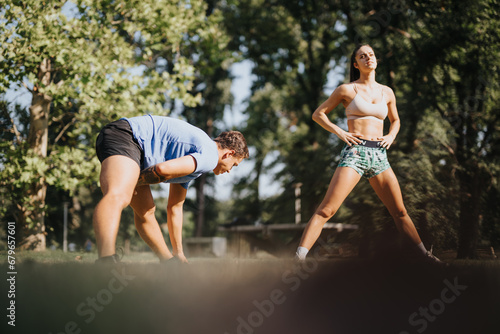 Two athletes warm up and stretch outdoors in a sunny park. They practice their fitness routine with a rope, surrounded by natural environment, inspiring motivation, and persistence.