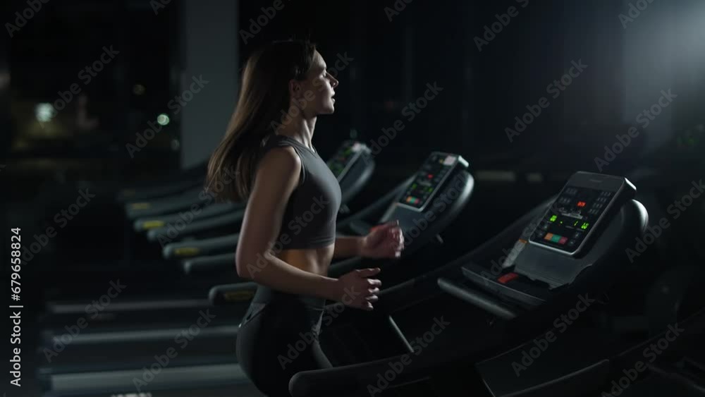 Wellness, young woman athlete run on a treadmill, aerobic exercise and endurance training in the gym, nightlife. Wellness, young woman athlete run on a treadmill, aerobic exercise and endurance training in the gym, nightlife.