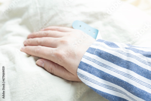 Close-up of patient's hands on hospital bed