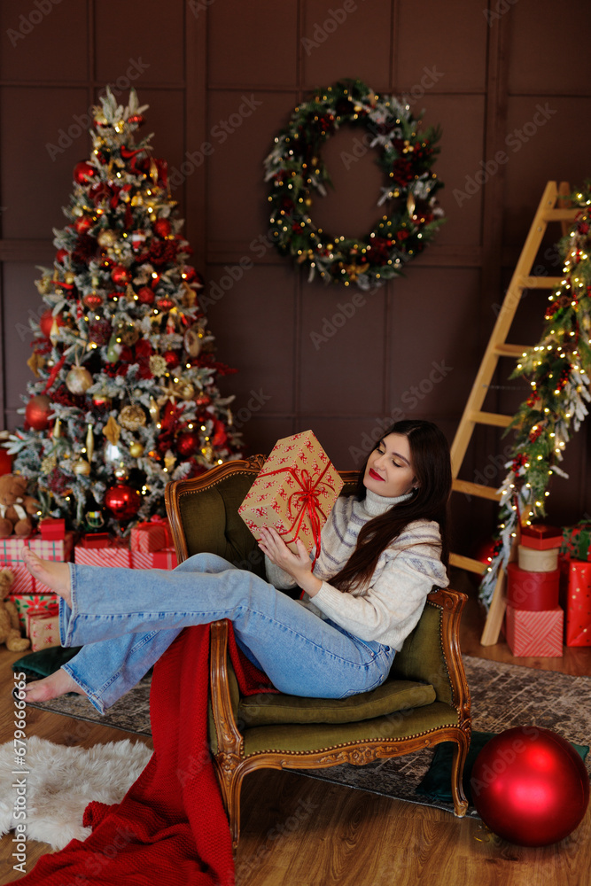 Woman in jeans and sweater sitiing on chair with gift