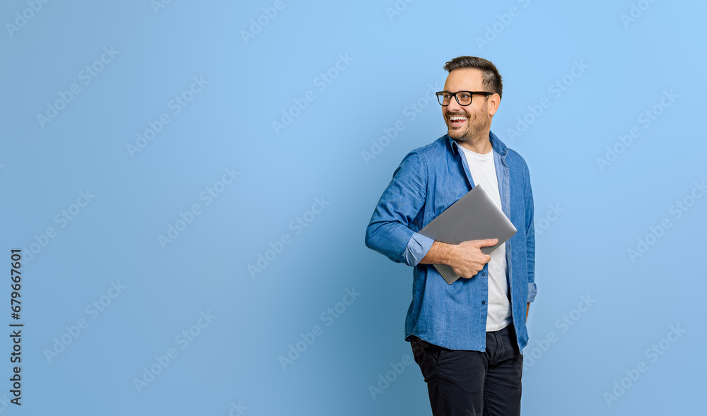 Smiling businessman holding digital tablet and looking over shoulder on blue background Smiling businessman holding digital tablet and looking over shoulder on blue background