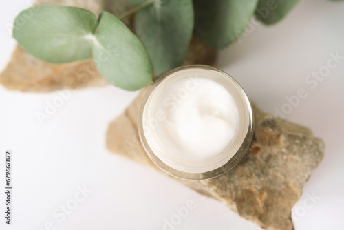 Close-up of skin care product  face cream texture. Cosmetic jar with eucalyptus on stone. Top view. Natural cosmetics concept