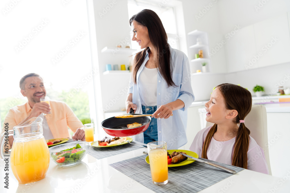 Portrait of small cute girl peaceful positive parents enjoy tasty homemade dish frying pan serving kitchen flat indoors Portrait of small cute girl peaceful positive parents enjoy tasty homemade dish frying pan serving kitchen flat indoors