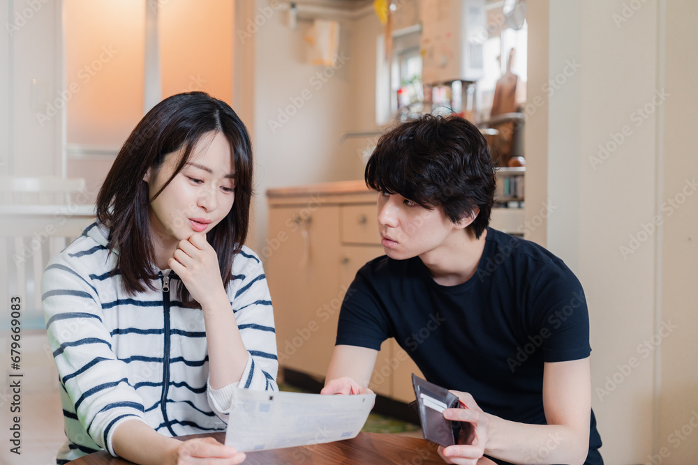 請求書明細を見て値上げに苦しむ若い夫婦 請求書明細を見て値上げに苦しむ若い夫婦