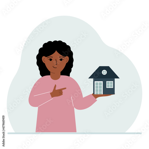 A little girl holds a small house in his palm. Concepts of inheritance or transfer of real estate to children.