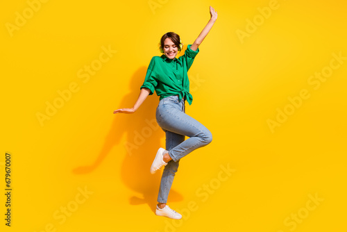 Full length photo of positive carefree girl dressed green shirt headphones dancing isolated yellow color background