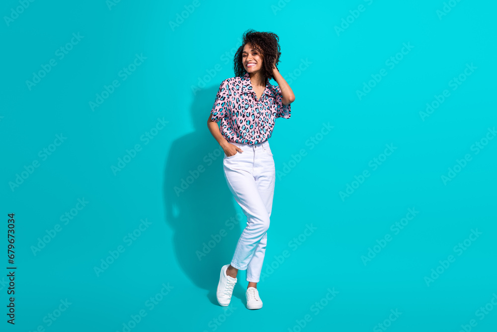 Full length photo of cheerful gorgeous girl dressed trendy clothes hand touch curly hairdo empty space isolated on cyan color background Full length photo of cheerful gorgeous girl dressed trendy clothes hand touch curly hairdo empty space isolated on cyan color background