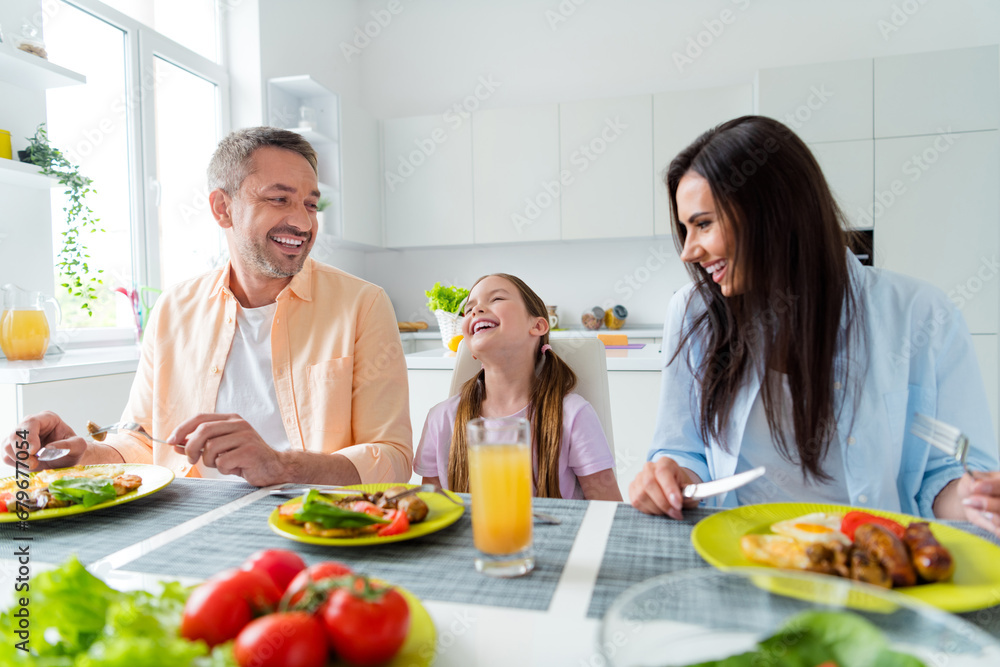 Photo of positive funky wife husband little girl laughing eating breakfast indoors apartment kitchen