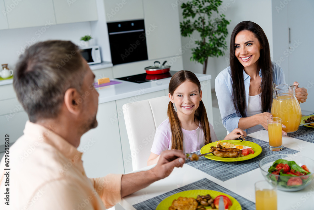 Portrait of beautiful family little girl cheerful satisfied parents eat homemade food drink fresh juice speak kitchen table indoors Portrait of beautiful family little girl cheerful satisfied parents eat homemade food drink fresh juice speak kitchen table indoors