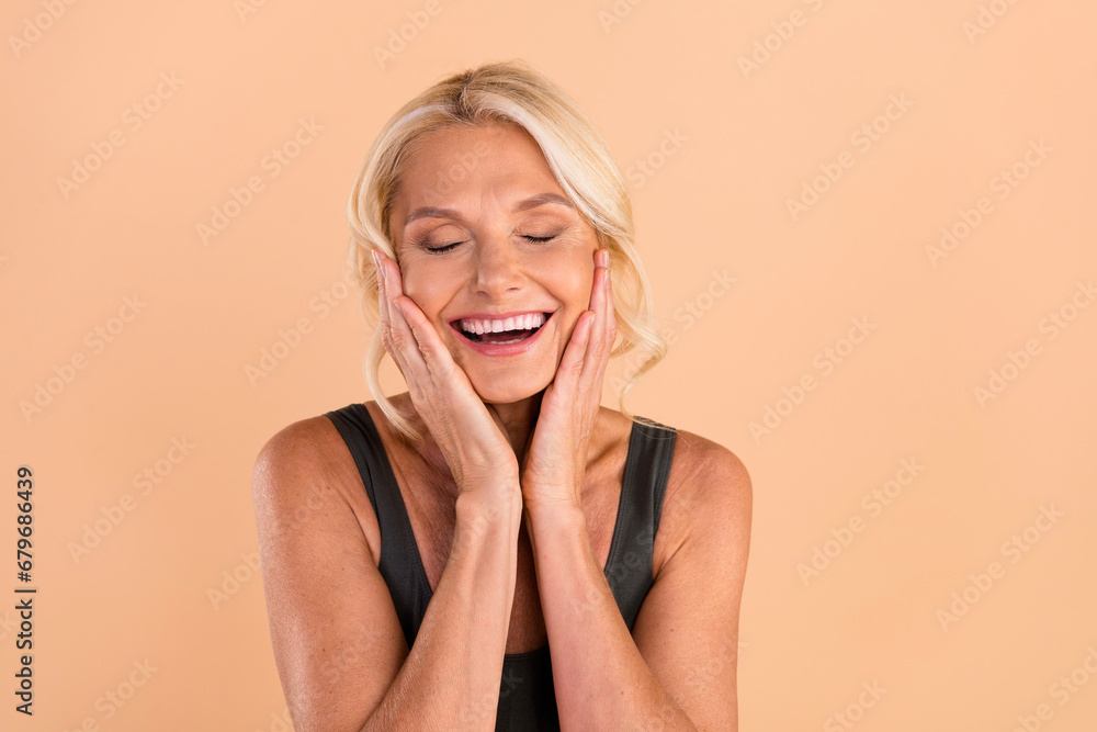 Photo of charming lovely woman touch tender soft skin after applying anti age wrinkle cream peeling isolated on beige color background Photo of charming lovely woman touch tender soft skin after applying anti age wrinkle cream peeling isolated on beige color background