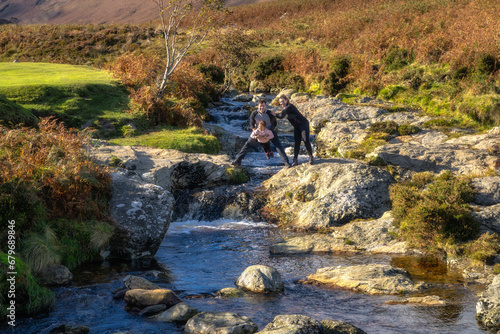 Family, mother, father and daughter having fun at mountain Dargle River. Hiking in Powerscourt, Wicklow Mountains at autumn, Ireland