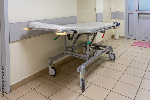 Empty medical mobile bed on wheels or stretcher trolley in hospital corridor photo