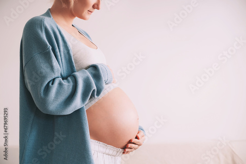 Beautiful pregnant woman hugging her belly in white background. Expectant mother waiting for baby birth during pregnancy. Concept of maternal health, visiting doctor and gynecological checkup. photo