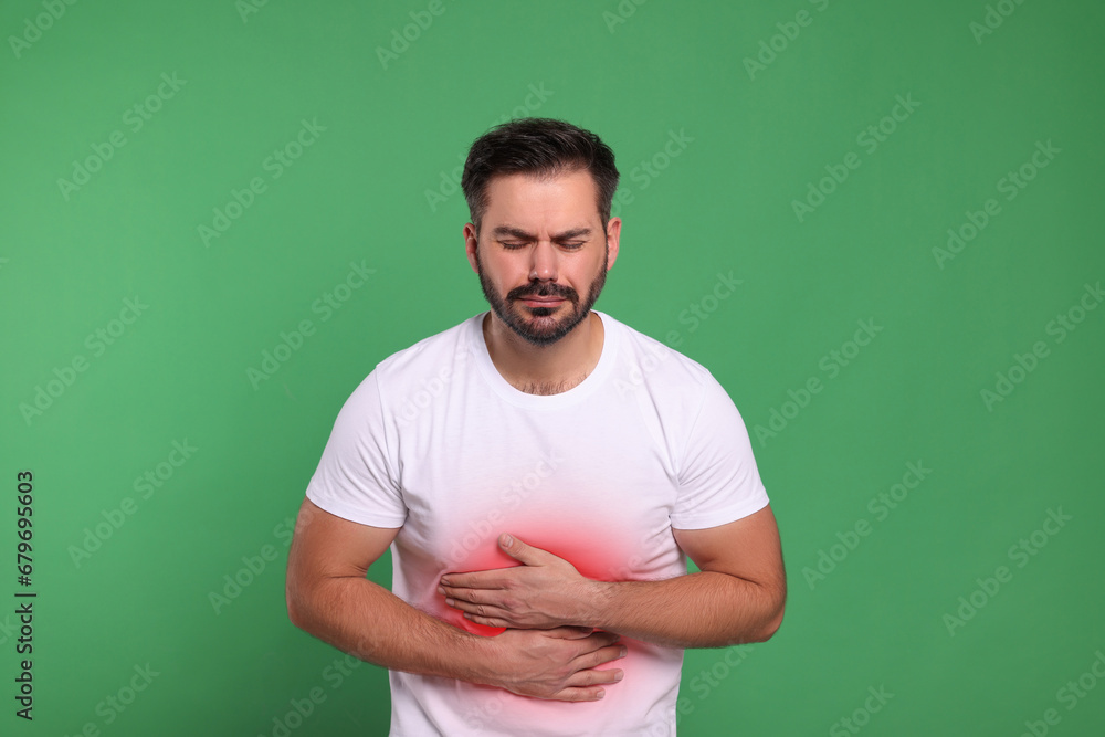 Fototapeta premium Man suffering from stomach pain on green background