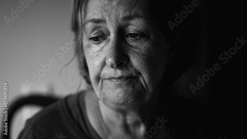 Senior woman struggling with depression, close-up face of dramatic elderly lady in quiet despair, preoccupied anxious emotion photo