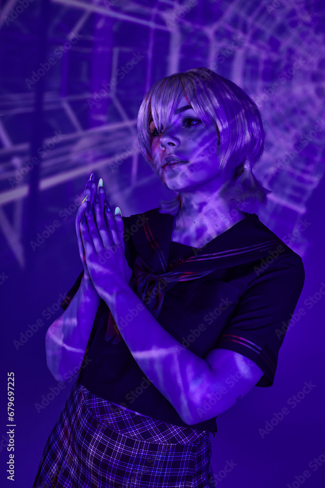 blonde cosplay woman in school uniform standing with praying hands in blue abstract projection blonde cosplay woman in school uniform standing with praying hands in blue abstract projection