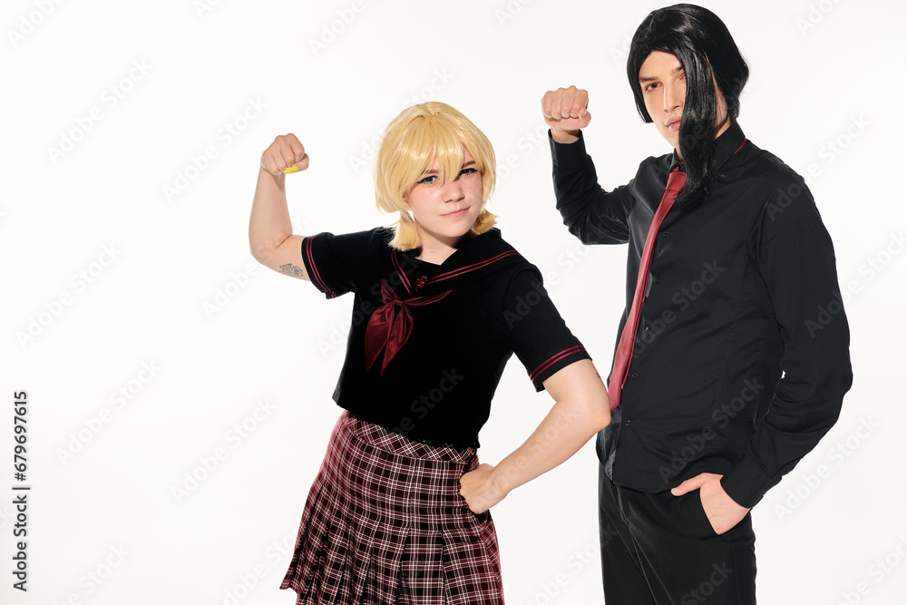 expressive students in dark uniform and wigs showing muscles and looking at camera on white expressive students in dark uniform and wigs showing muscles and looking at camera on white