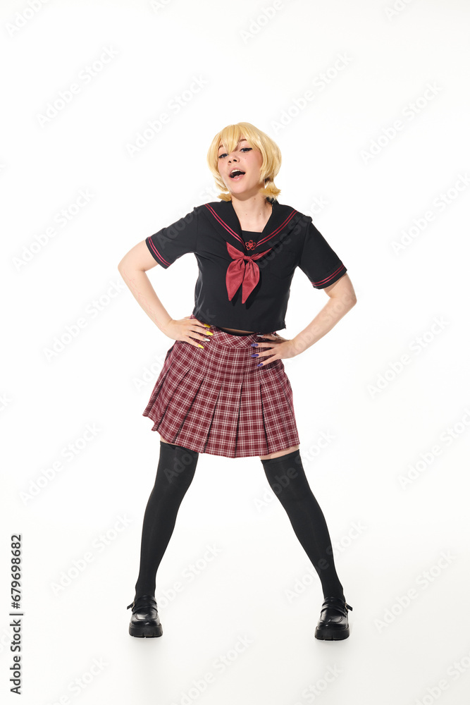 cosplay concept, woman in yellow blonde wig and school uniform posing with hands on hips on white cosplay concept, woman in yellow blonde wig and school uniform posing with hands on hips on white