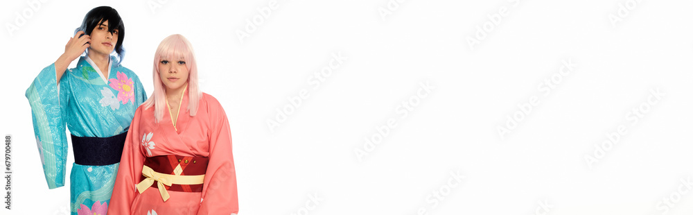 young cosplay couple in colorful kimonos and wigs looking at camera on white, horizontal banner young cosplay couple in colorful kimonos and wigs looking at camera on white, horizontal banner