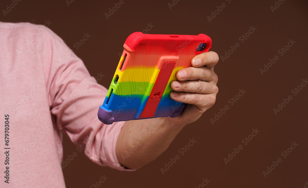 Sign of gay culture and LGBTQ pride representing man's hand holding pocket PC adorned in rainbow colors, Rainbow symbolism reflects diversity and inclusivity of LGBTQ community. Sign of gay culture and LGBTQ pride representing man's hand holding pocket PC adorned in rainbow colors, Rainbow symbolism reflects diversity and inclusivity of LGBTQ community.