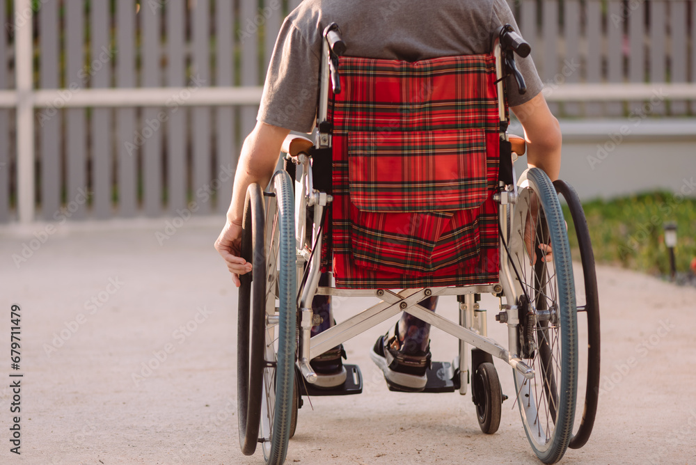 Obraz premium A young man with disabilities in relax time on beauty nature background,Lifestyle with disability person in the garden or park with safe wheel chair access, Concept of facilities for wheelchair users.