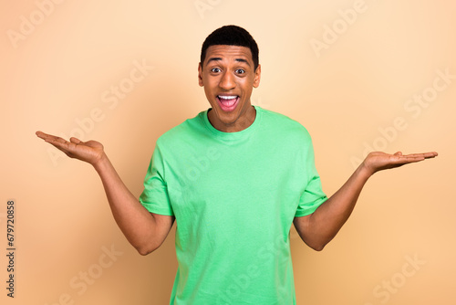 Photo portrait of attractive young man excited hands balance scales wear trendy green clothes isolated on beige color background