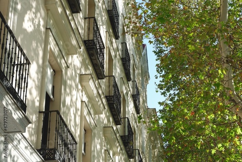 Elegant antique facade of beige colour seen through the greenery in barrio de Salamanca district, Madrid, Spain